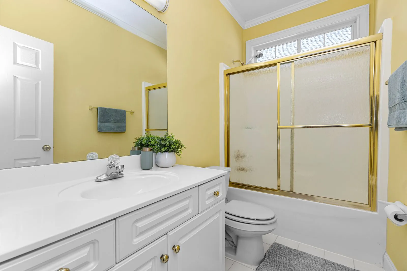 Bright yellow bathroom with white fixtures and gold accents, modern and clean.